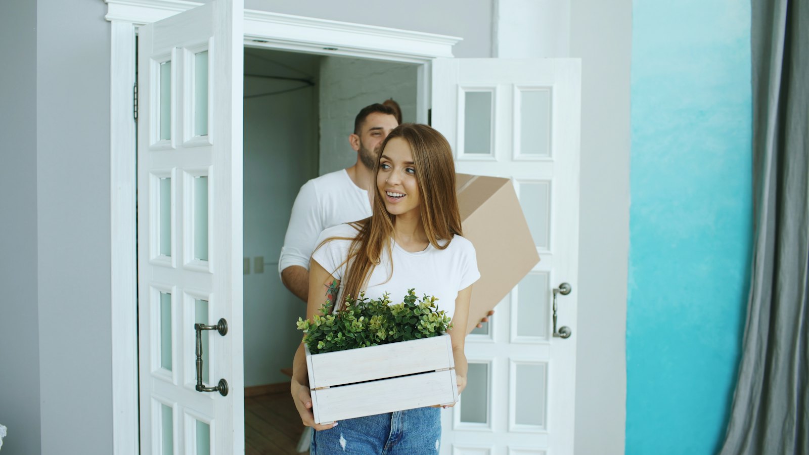 Casal chegando ao novo imóvel com caixas de mudança e plantas